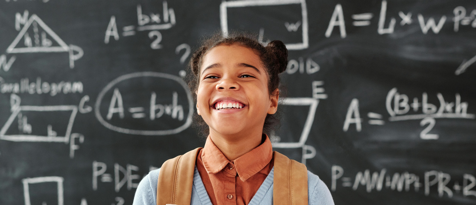 Child laughing in front of chalkboard